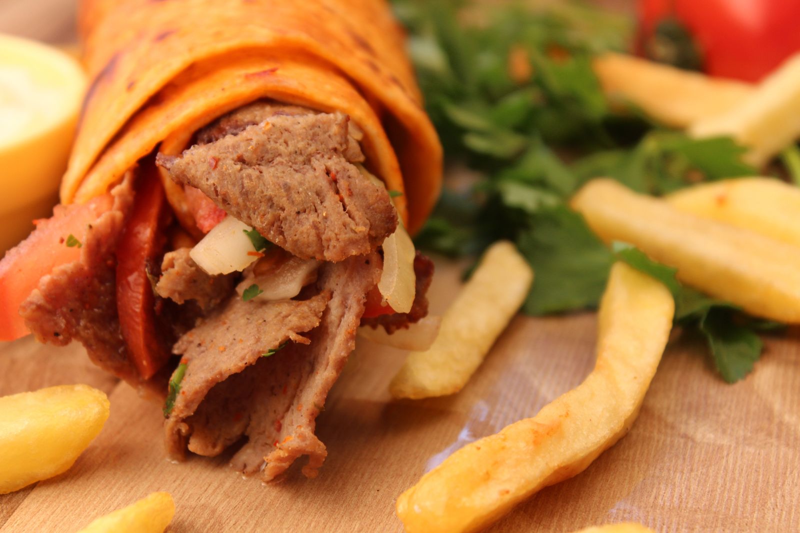 Fertig belegte Dönerrolle mit Pommes frites auf Holzuntergrund